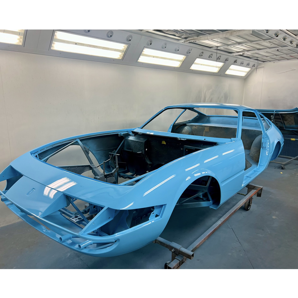 Classic automobile body undergoing restoration in a professional paint booth