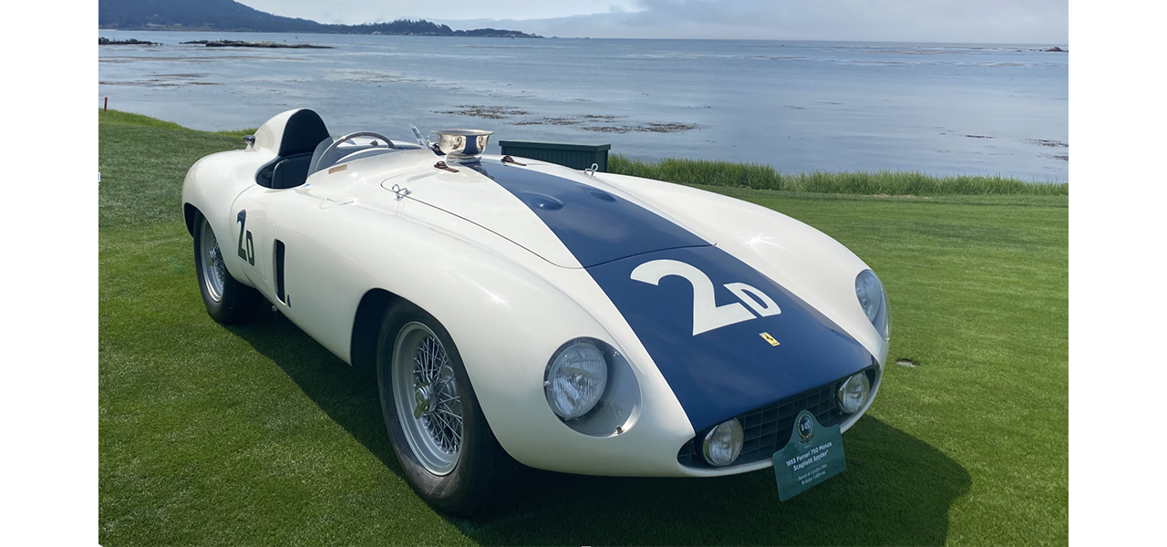 White and blue vintage Ferrari racing automobile displayed beside the coast